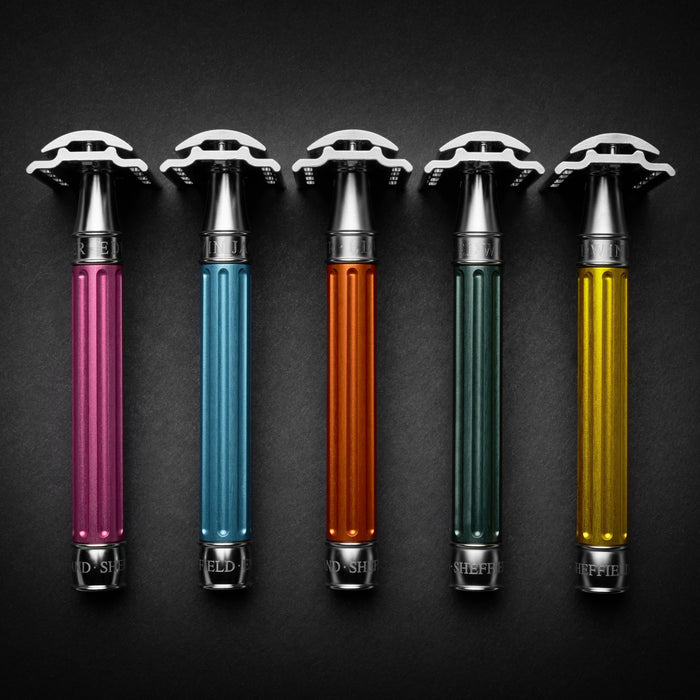 A row of colorful safety razors with sleek, metallic handles in pink, blue, orange, green, and yellow, arranged against a black background.