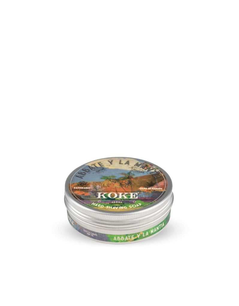 A solid shaving soap puck packaged in a metal tin with a label featuring a colorful illustration and text, indicating it is a product from Abbate y La Mantia, Koke brand, with a weight of 80g.