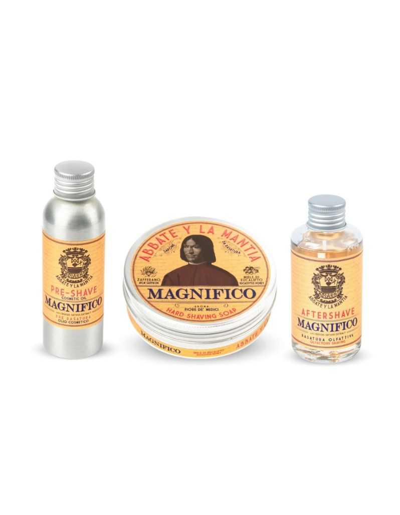 A set of three shaving products labeled 'MAGNIFIO' by Abbate y La Mantia, including a pre-shave oil, shaving soap, and aftershave lotion, presented in metal and plastic containers with orange and yellow labeling.