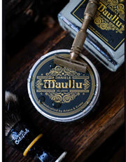 Daniele Maullu Legacy shaving soap tin with ornate black and gold label, barbershop oud scent, wet water droplets
