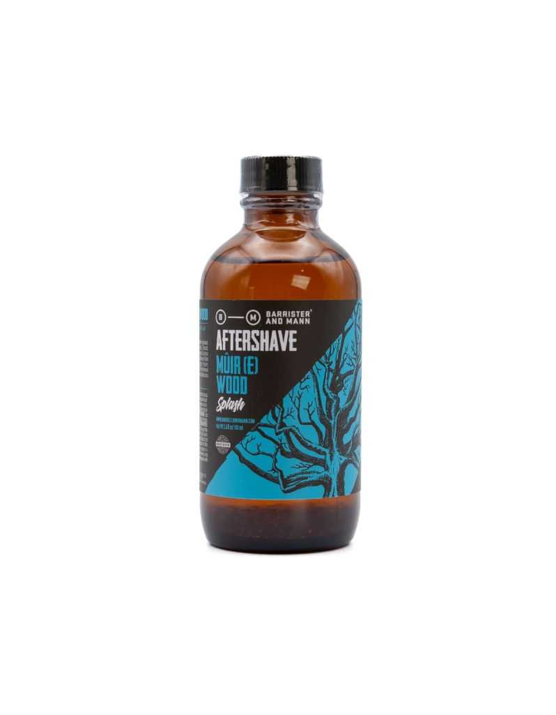 A bottle of Barrister and Mann aftershave splash with the label 'Mûre(e) Wood' featuring a design with blue and black colors, and the brand name visible.