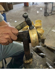 Artisan hand-hammering Captain’s Choice brass lather bowl during production