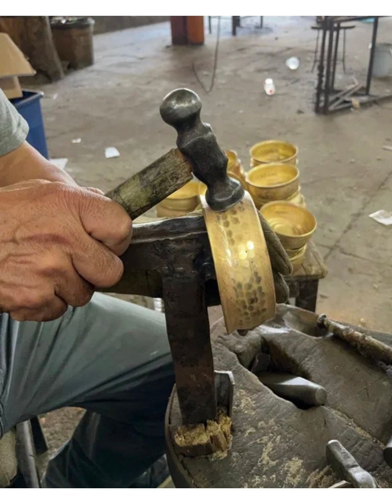 Artisan hand-hammering Captain’s Choice brass lather bowl during production