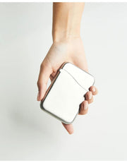 A hand holding the Craighill Summit Case, square, metallic silver case with rounded corners against a clean, light gray background.