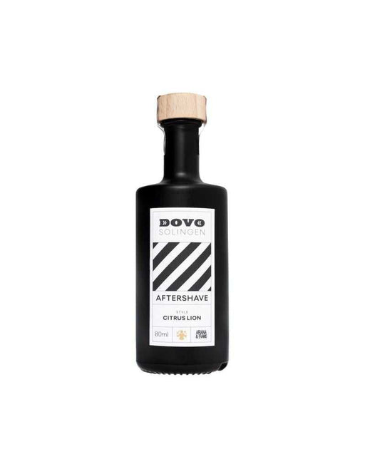 A aftershave bottle with black liquid, labeled 'DOVO AFTERSHAVE CITRUS LION', with a wooden cap.