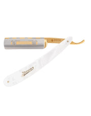 A straight razor with a white imitation pearl handle and gold-plated decorations, the blade is partially visible showing ornate engravings.