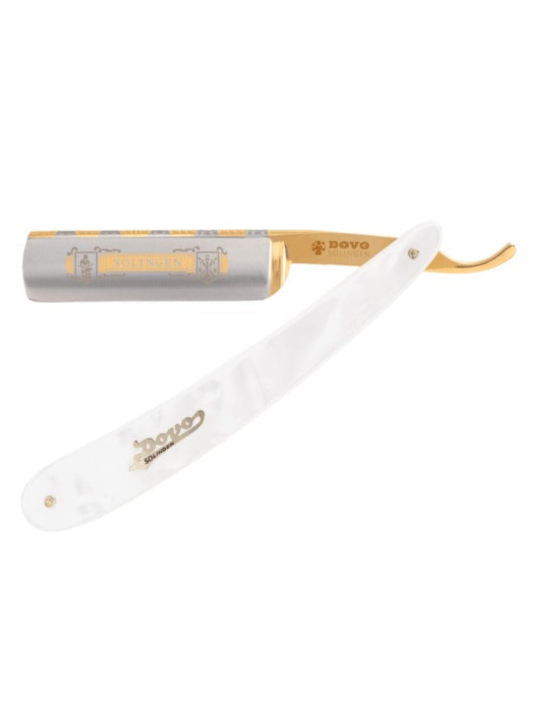 A straight razor with a white imitation pearl handle and gold-plated decorations, the blade is partially visible showing ornate engravings.