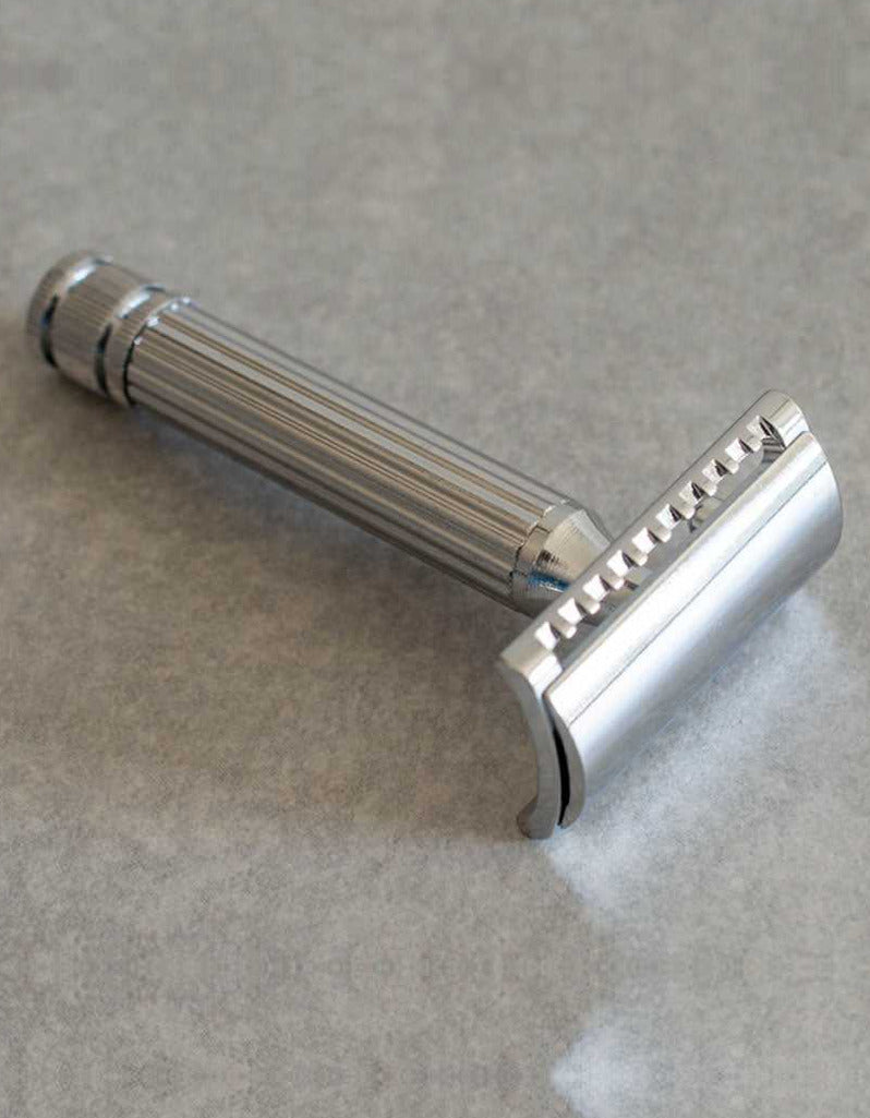 Fatip Classic chrome safety razor with a fluted handle and knurled end cap, resting on a gray stone surface