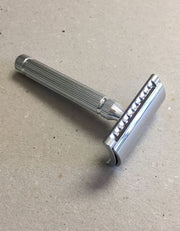 Fatip il Piccolo Gentle safety razor in chrome with a fluted handle, resting on a speckled gray surface