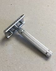 Back view of the Fatip il Piccolo Gentle chrome razor showing the baseplate and fluted handle on a gray surface