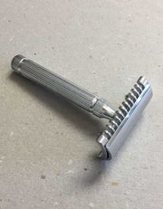 Fatip il Piccolo open comb safety razor in chrome with a fluted handle, resting on a speckled gray surface