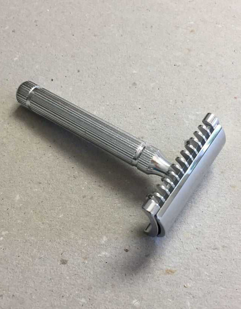 Fatip il Piccolo open comb safety razor in chrome with a fluted handle, resting on a speckled gray surface