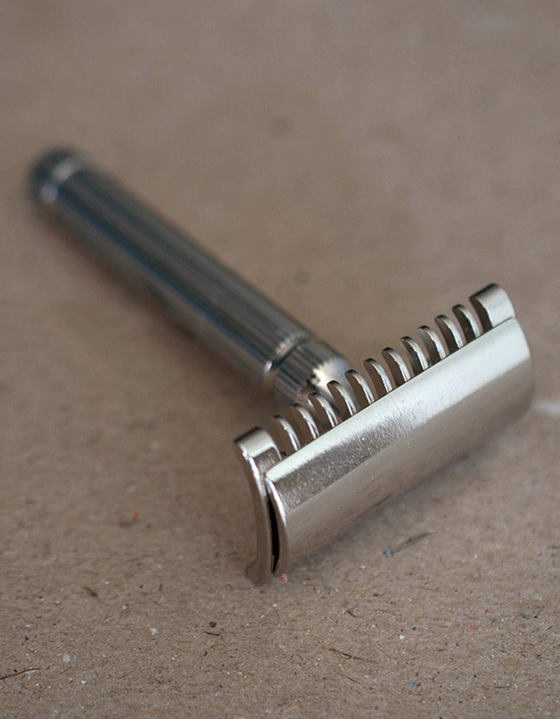 Fatip il Piccolo open comb safety razor in nickel with a fluted handle, resting on a brown kraft surface
