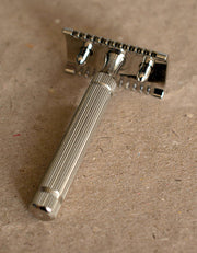 Back view of the Fatip il Piccolo nickel open comb razor showing the baseplate and fluted handle on kraft paper