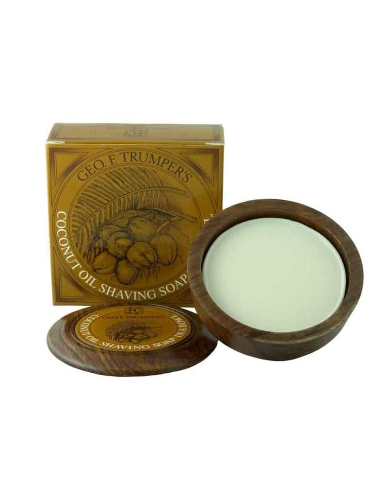 A wooden bowl containing Geo. F. Trumper Coconut Oil Shaving Soap, with the product's packaging box in the background.