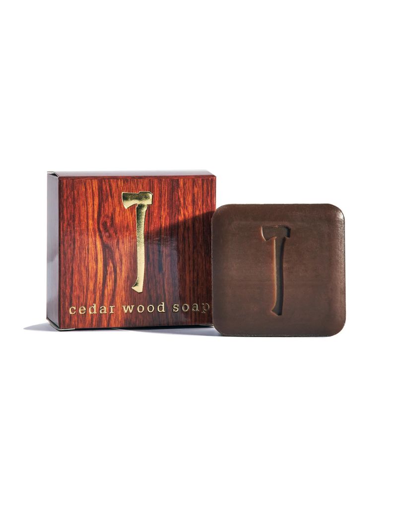 A bar of cedar wood soap next to its matching wooden looking cardboard box.