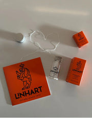 Linhart NYC Woven Floss glass jar, unwound floss, 25m and 4.6m boxes, and brochure on a white surface