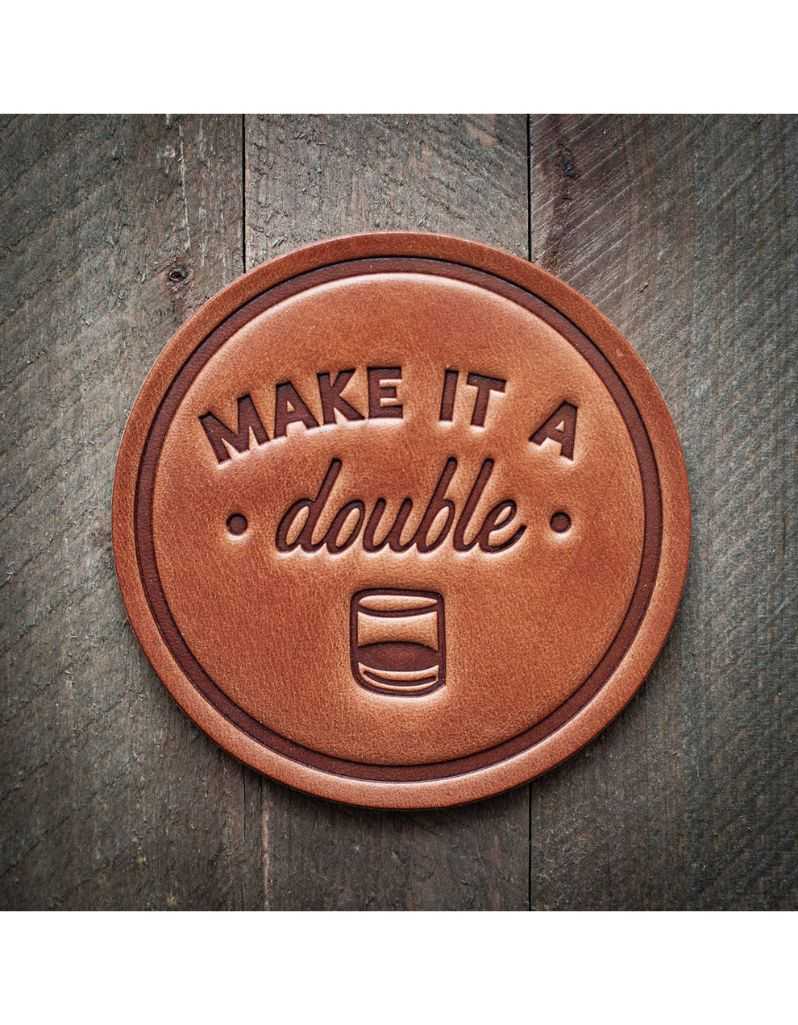 Brown leather coaster with 'MAKE IT A double' text on a wooden surface