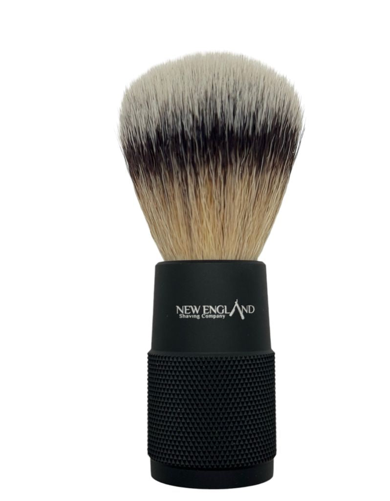 Shaving brush with black handle and bristle head on a white background, branded 'New England Shaving Company'.