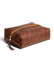 Brown leather toiletry bag with zipper on a white background