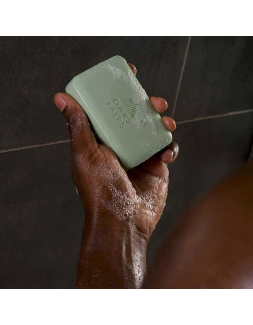Hand holding green Epsom Salt Bar Soap lathered with soap suds