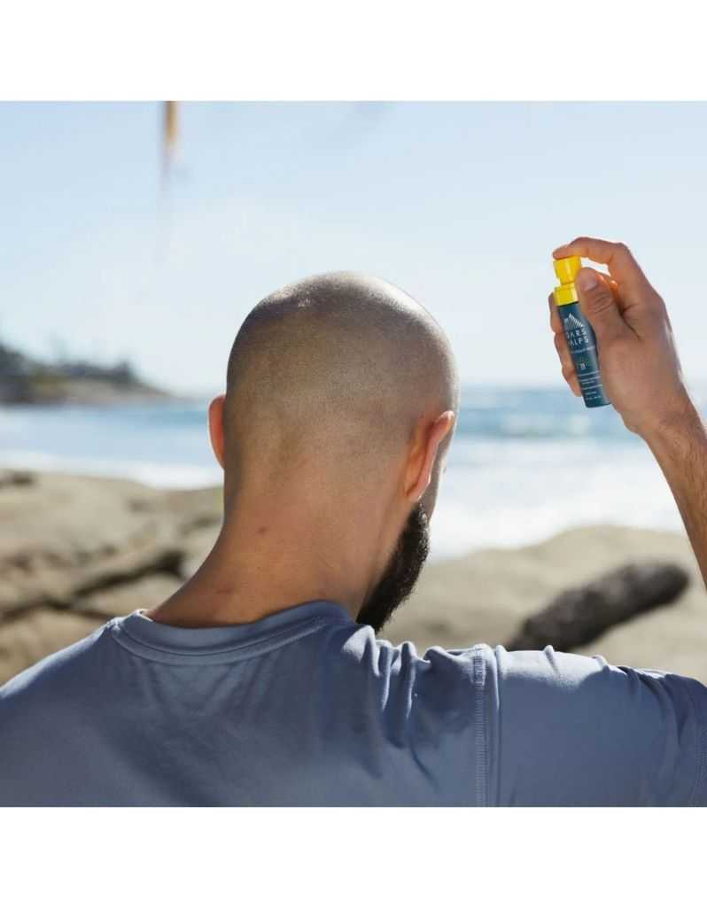 Man applying Oars + Alps SPF 35 mist on beach