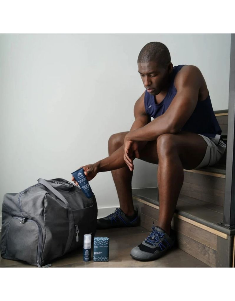 Man using muscle recovery balm on backpack