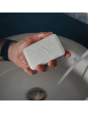 Oars + Alps Superfoliant Bar Soap in hand under running water