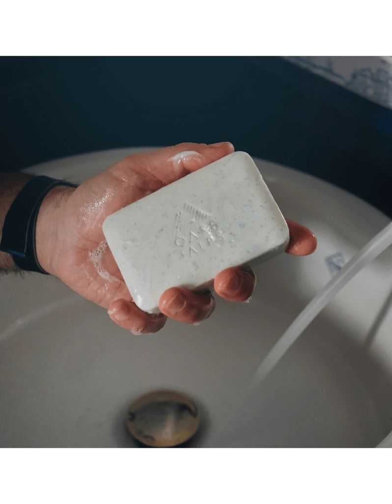 Oars + Alps Superfoliant Bar Soap in hand under running water