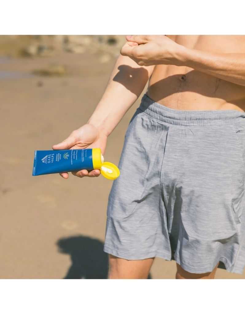 Person applying Oars + Alps SPF 35 sunscreen lotion on beach