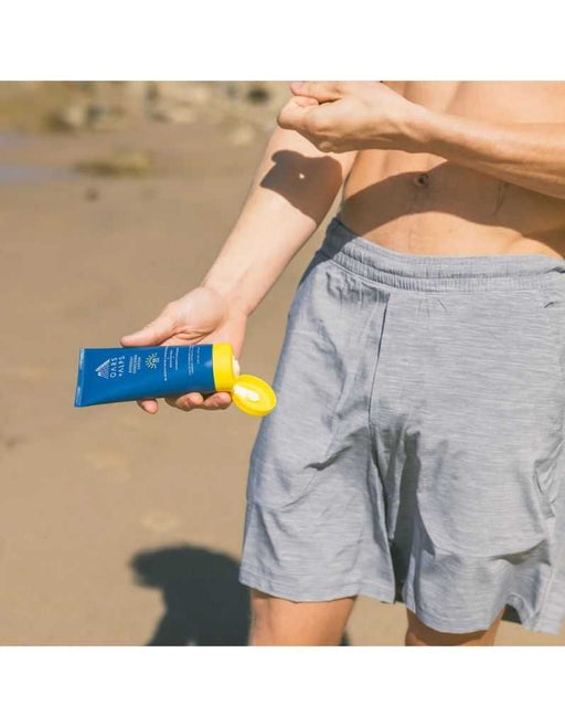 Person applying Oars + Alps SPF 35 sunscreen lotion on beach