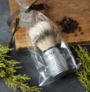 A boar bristle shaving brush with an aluminum handle, packaged in clear plastic, with a brown ribbon and tag.