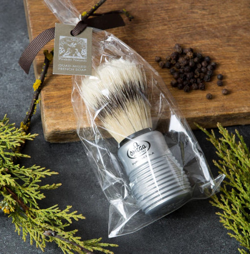 A boar bristle shaving brush with an aluminum handle, packaged in clear plastic, with a brown ribbon and tag.