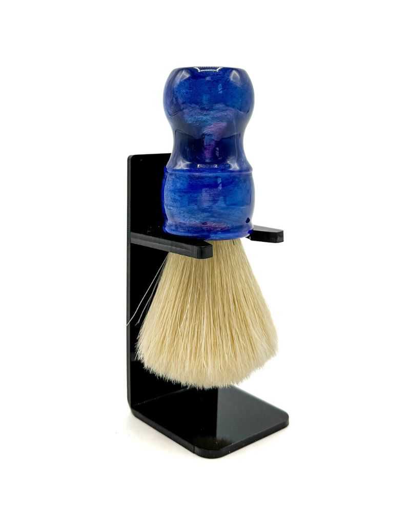 A boar bristle shaving brush with a blue iridescent resin handle, displayed in a black stand.