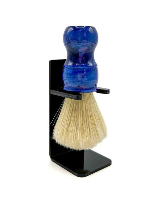 A boar bristle shaving brush with a blue iridescent resin handle, displayed in a black stand.