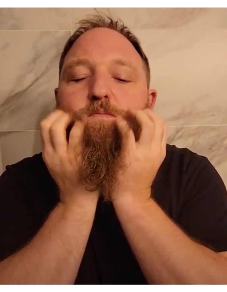 Applying hot oil beard treatment on long beard