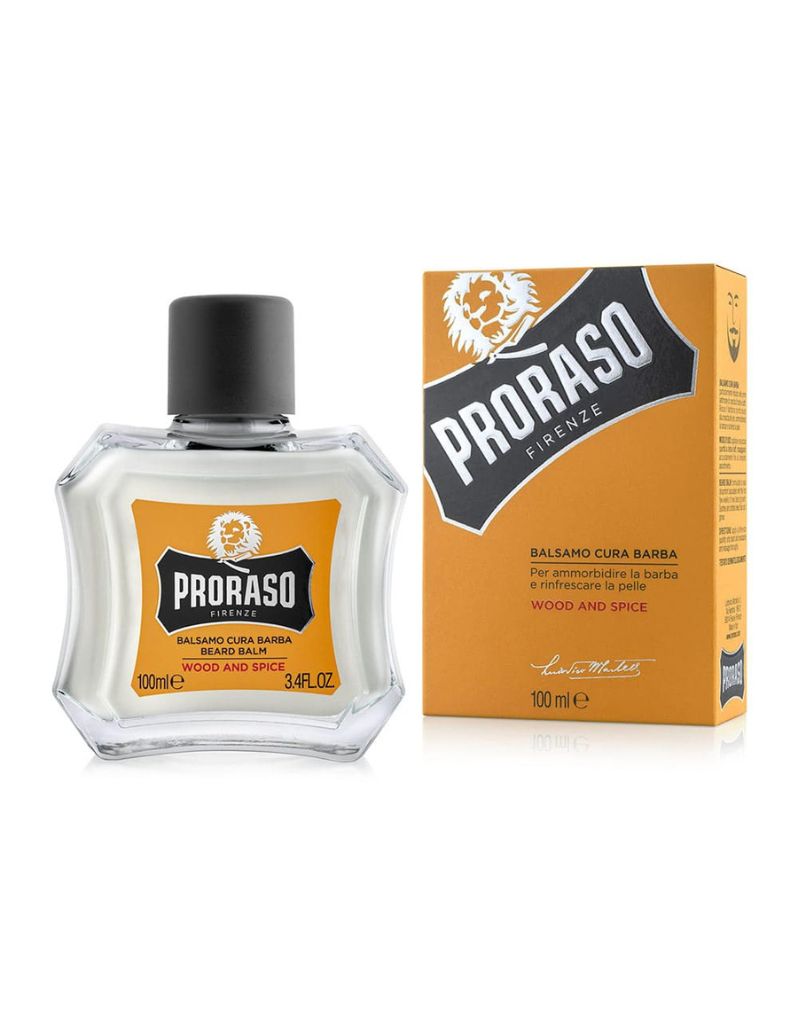 Proraso Beard Balm packaging and container, with the product name and scent 'Wood & Spice' indicated on the box. The balm is presented in a clear glass bottle with a black cap and a yellow label with black text.