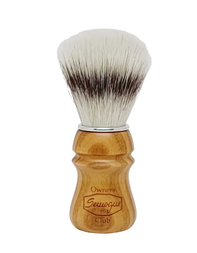 A Semogue shaving brush with synthetic bristles and a cherry wood handle with an aluminum ring at the base.