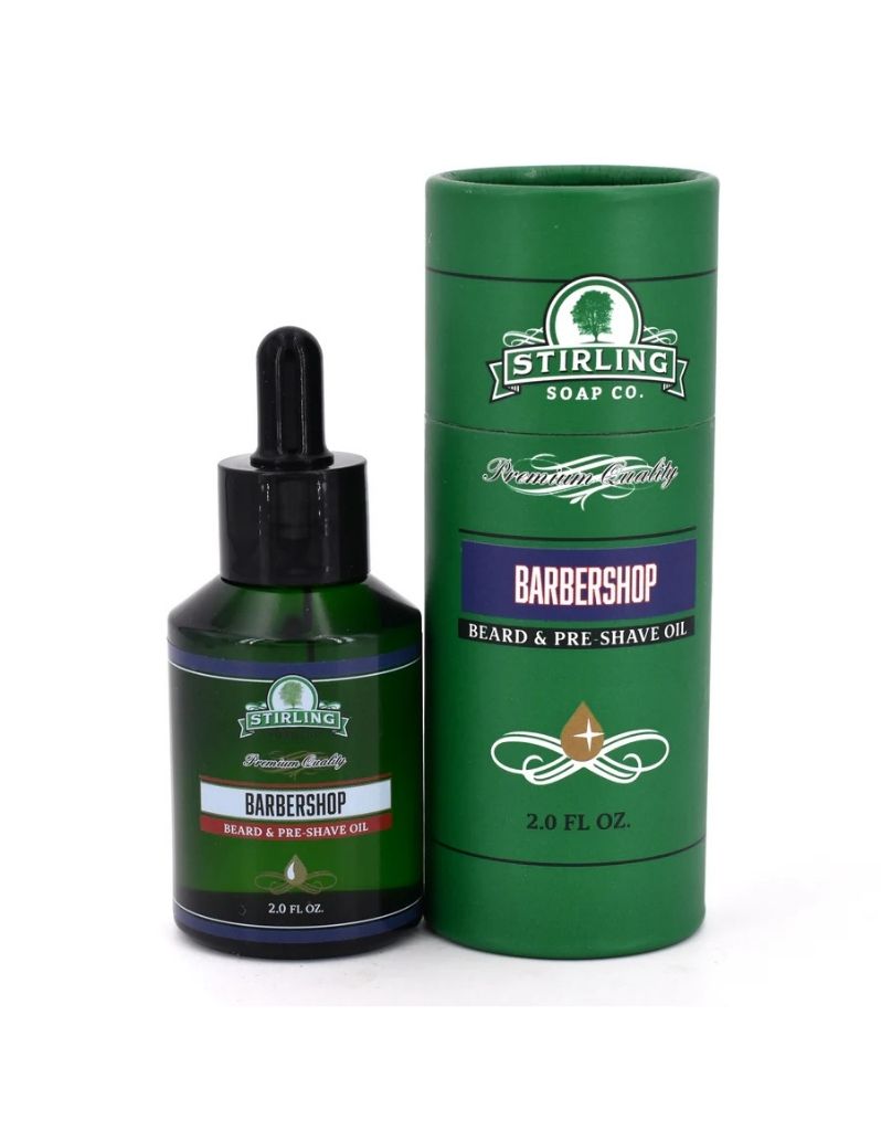 Stirling Soap Co. Barbershop Beard & Pre-Shave Oil shown in a dark green bottle with a black dropper cap next to its matching green cylindrical packaging tube on a white background.