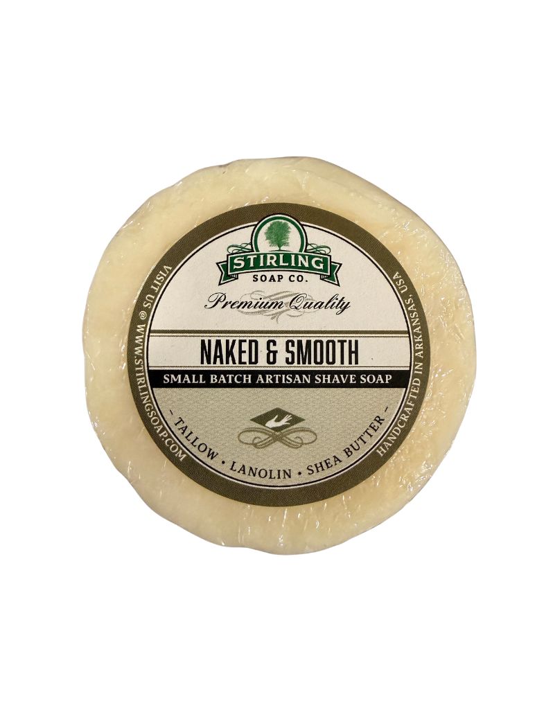 A round bar of Stirling Soap Co. Naked & Smooth artisan shave soap, featuring a cream-colored bar with a detailed circular label, set against a plain white background.