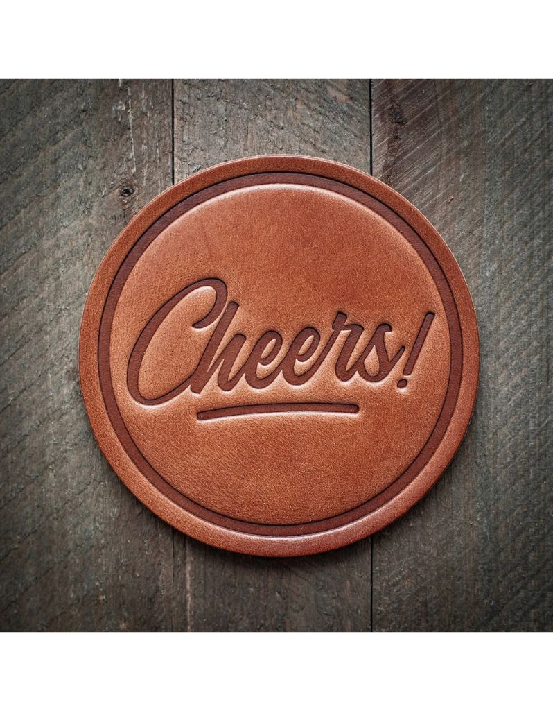 Handmade “Cheers!” leather coaster crafted from premium harness leather with a stamped celebratory design.