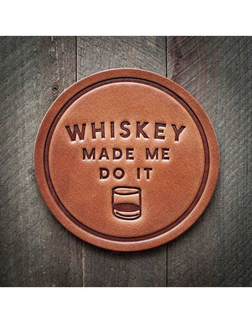 Round leather coaster with 'Whiskey Made Me Do It' text on a wooden background